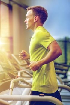 sport, fitness, lifestyle, technology and people concept - smiling man exercising on treadmill in gym. smiling man exercising on treadmill in gym