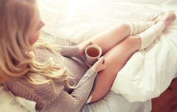 morning, leisure and people concept - close up of young woman with cup of tea in bed at home bedroom. close up of woman with tea cup in bed