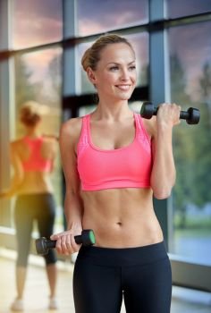 sport, fitness, training, weightlifting and people concept - young sporty woman with dumbbells flexing biceps in gym. young sporty woman with dumbbells flexing biceps