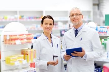 medicine, healthcare and technology concept - apothecaries with tablet pc computer and medication at pharmacy. apothecaries with tablet pc and drug at pharmacy