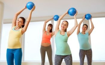 pregnancy, sport, fitness and healthy lifestyle concept - group of happy pregnant women training with small exercise balls in gym. pregnant women training with exercise balls in gym