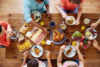 food, eating and family concept - group of people having breakfast and sitting at table. group of people having breakfast at table