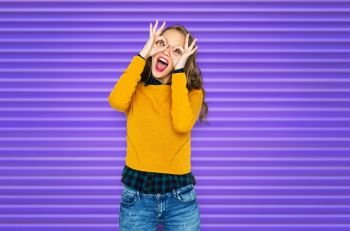 people, style and fashion concept - happy young woman or teen girl in casual clothes having fun and making faces over ultra violet background. happy young woman or teen girl making faces