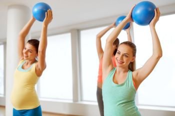 pregnancy, sport, fitness and healthy lifestyle concept - group of happy pregnant women training with small exercise balls in gym. pregnant women training with exercise balls in gym. pregnant women training with exercise balls in gym