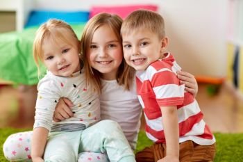 childhood, leisure and family concept - happy little kids hugging at home. happy little kids hugging at home. happy little kids hugging at home