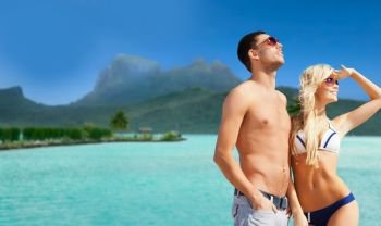 travel, tourism and summer holidays concept - happy couple in sunglasses at touristic resort over exotic bora bora island background. happy couple on over bora bora background. happy couple on over bora bora background