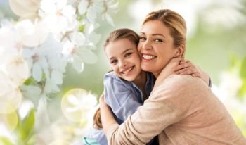 people and family concept - happy smiling mother hugging daughter over cherry blossom background. happy mother hugging daughter over cherry blossom. happy mother hugging daughter over cherry blossom