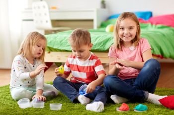 childhood, leisure and people concept - group of kids with modelling clay or slimes at home. kids with modelling clay or slimes at home. kids with modelling clay or slimes at home