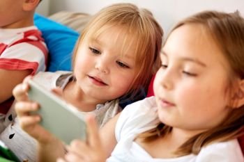 childhood, technology and family concept - happy little kids with smartphone in bed at home. little kids with smartphone in bed at home. little kids with smartphone in bed at home