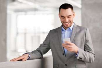 business people, technology and corporate concept - smiling businessman with smarphone at office. smiling businessman with smarphone at office. smiling businessman with smarphone at office