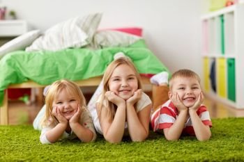 childhood, leisure and family concept - happy little kids lying on floor or carpet. happy little kids lying on floor or carpet. happy little kids lying on floor or carpet
