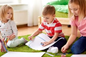 childhood, creativity, family and people concept - happy creative kids with paper, crayons and adhesive tape drawing and making crafts at home. happy creative kids making crafts at home. happy creative kids making crafts at home