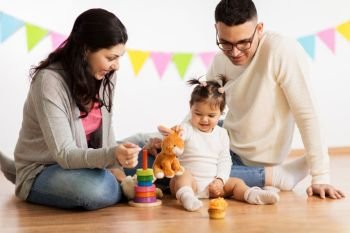 family, holidays and people concept - happy mother, father and little daughter playing with toy rabbit on birthday party. baby girl with parents playing with toy rabbit. baby girl with parents playing with toy rabbit