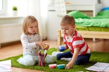 childhood, leisure and people concept - little kids with modelling clay and crayons at home. kids with modelling clay and crayons at home. kids with modelling clay and crayons at home