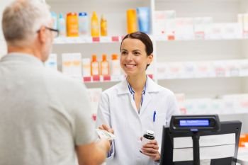 medicine, pharmaceutics, health care and people concept - apothecary and senior man customer buying drug at drugstore. apothecary selling drug to senior man at pharmacy. apothecary selling drug to senior man at pharmacy
