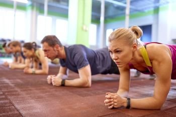 fitness, sport, exercising and people concept - woman with heart-rate tracker at group training doing plank exercise in gym. woman with heart-rate tracker exercising in gym. woman with heart-rate tracker exercising in gym
