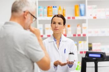 medicine, pharmaceutics, health care and people concept - apothecary showing drug to senior man customer at drugstore. apothecary showing drug to senior man at pharmacy. apothecary showing drug to senior man at pharmacy