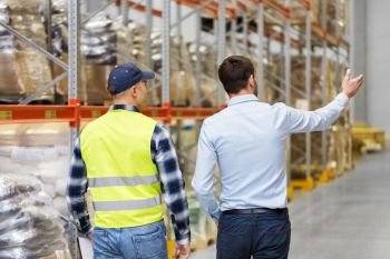 logistic business and people concept - businessman showing warehouse to worker. businessman showing warehouse to worker. businessman showing warehouse to worker