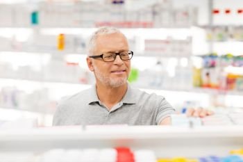 medicine, pharmaceutics, healthcare and people concept - senior male customer with drug at pharmacy. senior male customer with drug at pharmacy. senior male customer with drug at pharmacy