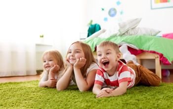 childhood, leisure and family concept - happy little kids lying on floor or carpet. happy little kids lying on floor or carpet. happy little kids lying on floor or carpet