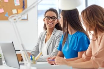 business, teamwork and people concept - female team or businesswomen talking at office. businesswomen talking at office. businesswomen talking at office