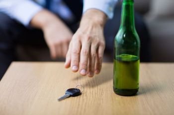 alcohol abuse, drunk driving and people concept - close up of beer bottle and male driver hand taking car key from table. drunk driver hand taking car key from table. drunk driver hand taking car key from table