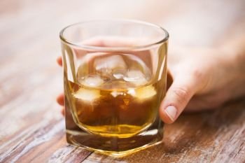 alcoholism, alcohol addiction and people concept - close up of male hand with glass of whiskey on table. male hand with glass of alcohol on table. male hand with glass of alcohol on table