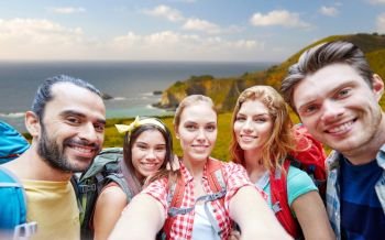 technology, travel, tourism, hike and people concept - group of smiling friends with backpacks taking selfie over big sur coast of california background. friends with backpack taking selfie over big sur. friends with backpack taking selfie over big sur