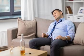 alcoholism, alcohol addiction and people concept - male alcoholic with glass of whiskey sleeping on sofa at home. drunk man with glass of alcohol sleeping at home. drunk man with glass of alcohol sleeping at home