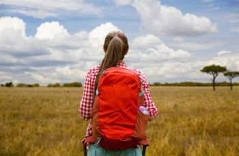 adventure, travel, tourism, hike and people concept - young woman with backpack over african savannah background. woman with backpack over african savannah. woman with backpack over african savannah