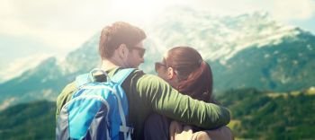 travel, tourism and people concept - happy couple with backpacks hugging over alps mountains background. happy couple with backpacks traveling. happy couple with backpacks traveling