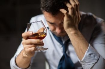 alcoholism, alcohol addiction and people concept - close up of male alcoholic drinking brandy at night. close up of drunk man drinking alcohol at night. close up of drunk man drinking alcohol at night