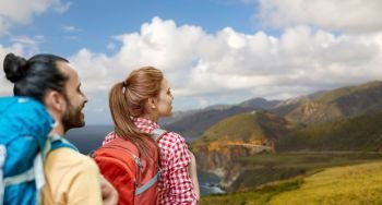 travel, tourism, hike and adventure concept - couple of travelers with backpacks over bixby creek bridge on big sur coast of california background. couple with backpacks on big sur coast. couple with backpacks on big sur coast