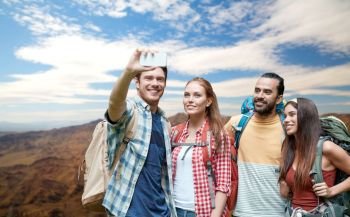 technology, travel, tourism, hike and people concept - group of smiling friends with backpacks taking selfie by smartphone over grand canyon national park hills background. friends with backpack taking selfie by smartphone. friends with backpack taking selfie by smartphone