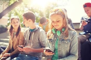 technology, internet and people concept - group of happy teenage friends with smartphone and headphones outdoors. teenage friends with smartphone and headphones. teenage friends with smartphone and headphones