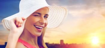 summer, fashion and people concept - portrait of beautiful smiling woman in sun hat over city sunset background. beautiful smiling woman in sun hat over sunset. beautiful smiling woman in sun hat over sunset