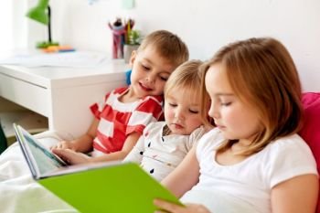 childhood, leisure and family concept - little kids reading book in bed at home. little kids reading book in bed at home. little kids reading book in bed at home