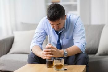 alcoholism, alcohol addiction and people concept - male alcoholic with bottle and drinking whiskey at home. alcoholic with bottle drinking whiskey at home. alcoholic with bottle drinking whiskey at home