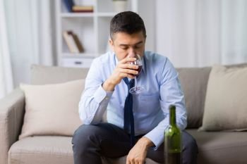 alcoholism, alcohol addiction and people concept - male alcoholic drinking glass of red wine at home. alcoholic drinking red wine at home. alcoholic drinking red wine at home