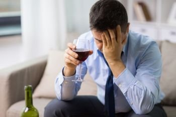alcoholism, alcohol addiction and people concept - male alcoholic drinking glass of red wine at home. alcoholic drinking red wine at home. alcoholic drinking red wine at home