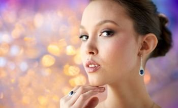 beauty, jewelry, people and luxury concept - close up of beautiful asian woman or bride with earring and finger ring over holidays lights background. beautiful woman with earring and finger ring. beautiful woman with earring and finger ring