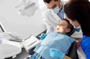 medicine, dentistry and healthcare concept - dentist with mouth mirror checking for kid patient teeth at dental clinic. dentist checking for kid teeth at dental clinic. dentist checking for kid teeth at dental clinic