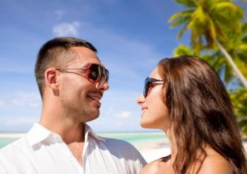 travel, tourism and summer vacation concept - happy smiling couple in sunglasses over tropical beach background in french polynesia. happy couple in sunglasses over tropical beach. happy couple in sunglasses over tropical beach