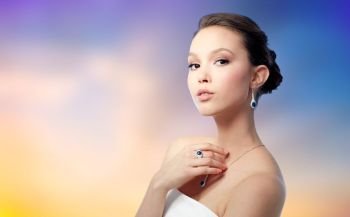 beauty, jewelry and luxury concept - beautiful asian woman or bride with earring, finger ring and pendant over pastel background. beautiful woman with earring, ring and pendant. beautiful woman with earring, ring and pendant