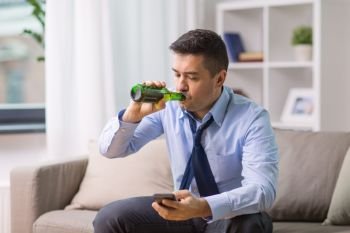 alcoholism, alcohol addiction and people concept - male alcoholic with smartphone drinking bottled beer at home. alcoholic with smartphone drinking beer at home. alcoholic with smartphone drinking beer at home
