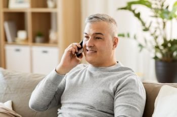 technology, people and communication concept - happy man calling on smartphone at home. happy man calling on smartphone at home. happy man calling on smartphone at home