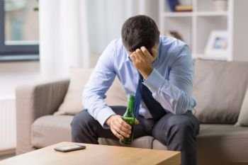 alcoholism, alcohol addiction and people concept - male alcoholic drinking beer from bottle at home. male alcoholic drinking beer at home. male alcoholic drinking beer at home
