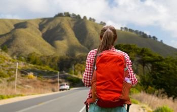 travel, tourism and hike concept - young woman with backpack over big sur of california hills background. woman with backpack traveling over big sur hills. woman with backpack traveling over big sur hills