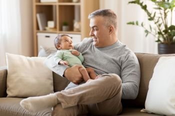 family, fatherhood and people concept - happy father with little baby boy sitting on sofa at home. happy father with little baby boy at home. happy father with little baby boy at home