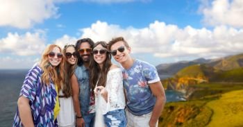 tourism, travel and summer holidays concept - smiling young hippie friends taking picture by selfie stick over big sur coast of california background. hippie friends taking picture by selfie stick. hippie friends taking picture by selfie stick